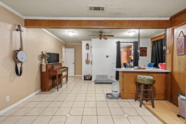 kitchen with a breakfast bar, ornamental molding, ceiling fan, kitchen peninsula, and a textured ceiling