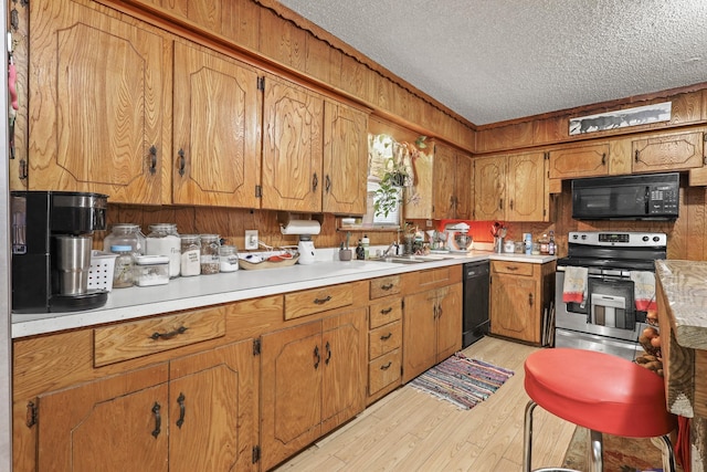 kitchen with sink, a textured ceiling, light hardwood / wood-style floors, and black appliances