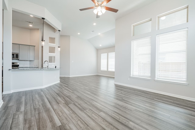 unfurnished living room with ceiling fan, wood-type flooring, and vaulted ceiling