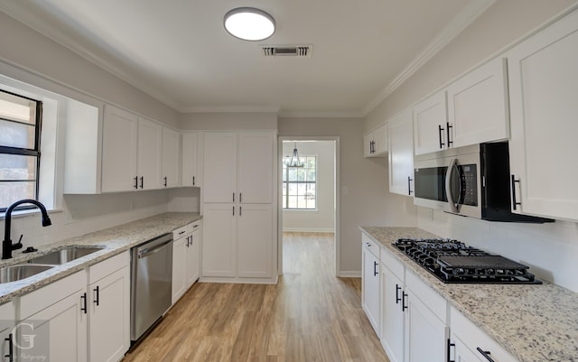 kitchen featuring appliances with stainless steel finishes, sink, white cabinets, and light hardwood / wood-style flooring