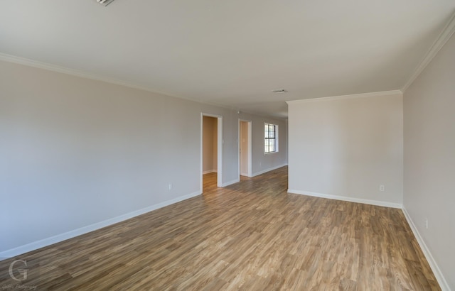 empty room featuring wood-type flooring and ornamental molding