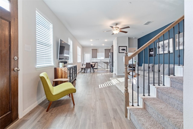 foyer entrance with ceiling fan and light hardwood / wood-style floors