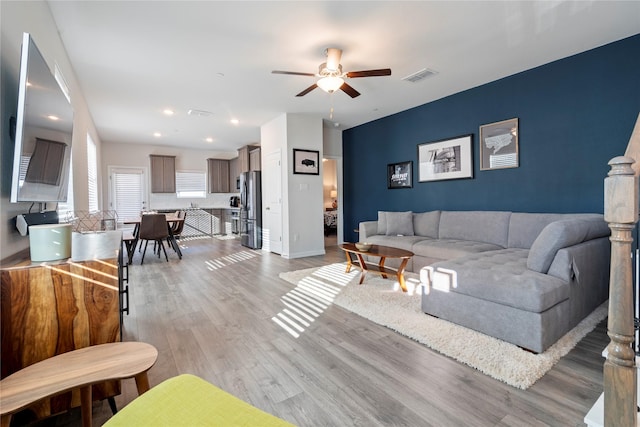 living room with light hardwood / wood-style flooring and ceiling fan