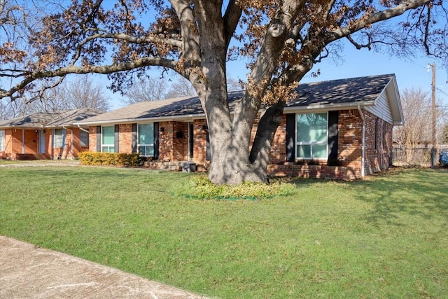 ranch-style house with a front lawn, fence, and brick siding