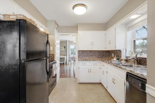 kitchen with decorative backsplash, white cabinets, light countertops, black appliances, and a sink