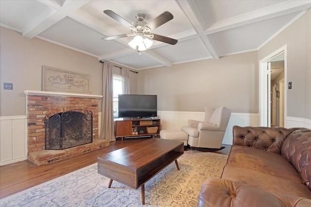 living room featuring beamed ceiling, coffered ceiling, ceiling fan, a brick fireplace, and light wood-type flooring