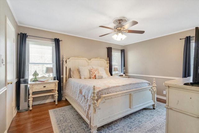 bedroom featuring ornamental molding, multiple windows, a ceiling fan, and light wood-style floors