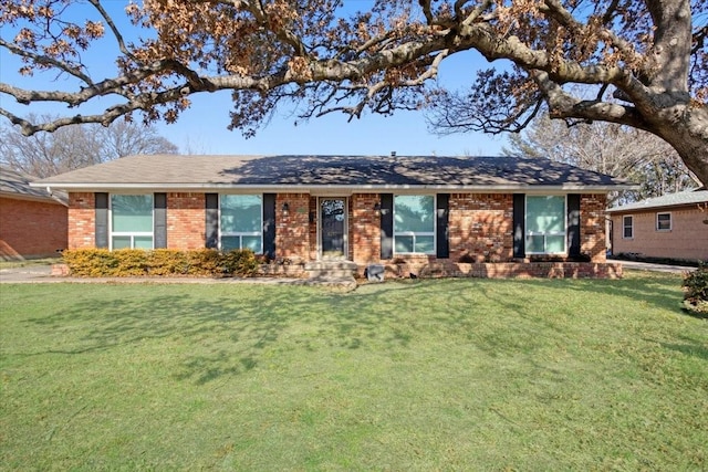 ranch-style house featuring brick siding, a shingled roof, and a front yard