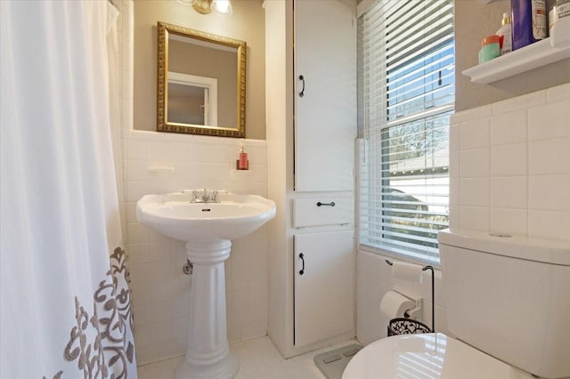 bathroom featuring toilet, a shower with shower curtain, tile walls, and a wealth of natural light