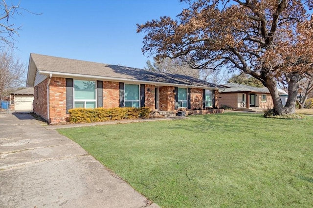 ranch-style home featuring brick siding, an outdoor structure, and a front yard