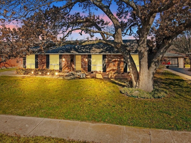 ranch-style house featuring brick siding and a yard