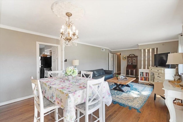 dining area with ornamental molding, wood-type flooring, and a chandelier