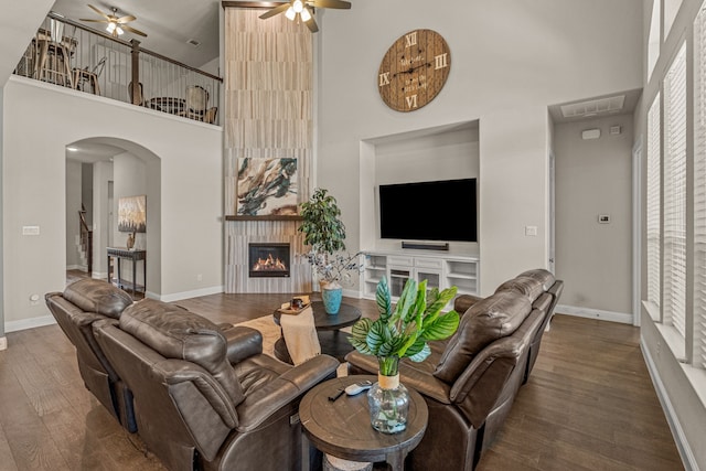 920 Windrock Ln, Prosper, TX 75078 - living area with ceiling fan, a high ceiling, arched walkways, a fireplace, and wood finished floors