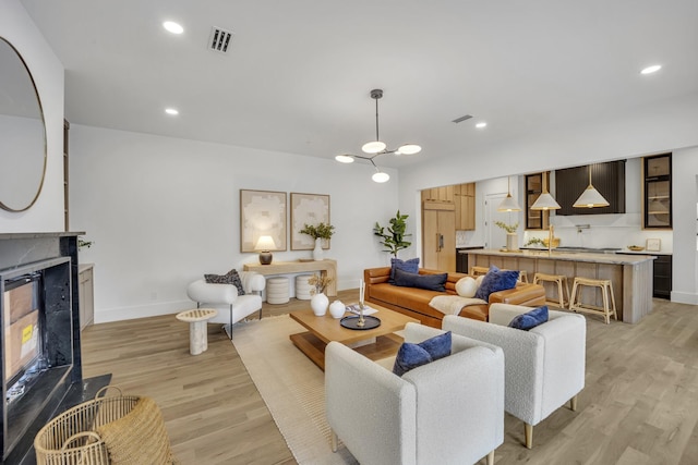 living room featuring a high end fireplace and light hardwood / wood-style flooring