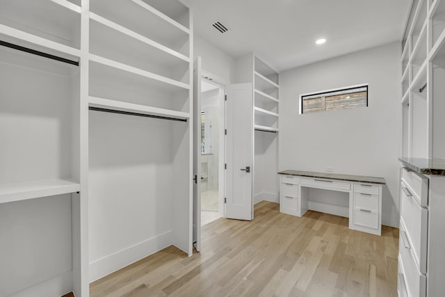 walk in closet with light hardwood / wood-style floors