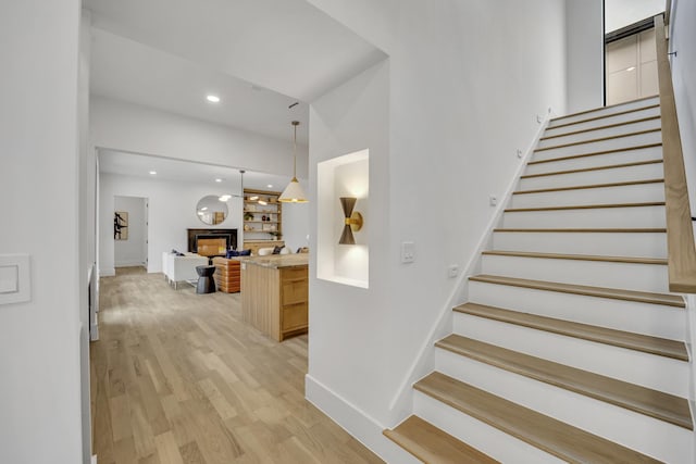 staircase featuring wood-type flooring and built in shelves