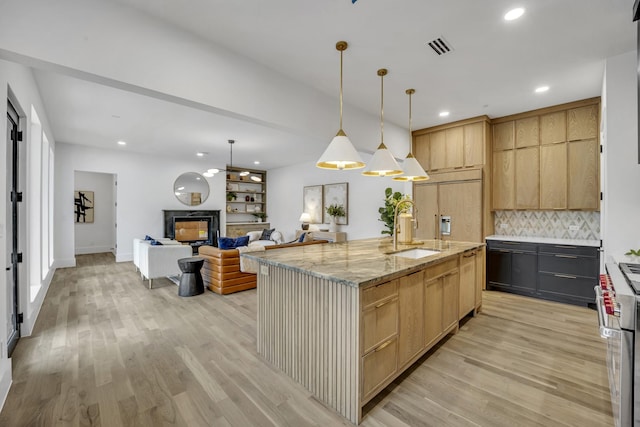 kitchen with decorative light fixtures, sink, high end appliances, a large island, and light stone countertops