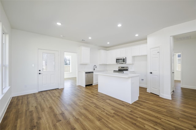 kitchen featuring sink, wood-type flooring, a center island, stainless steel appliances, and white cabinets