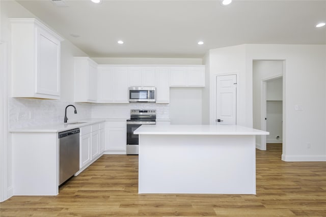 kitchen with stainless steel appliances, a center island, light wood-type flooring, and white cabinets