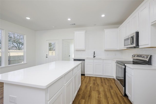 kitchen with stainless steel appliances, tasteful backsplash, a center island, and white cabinets