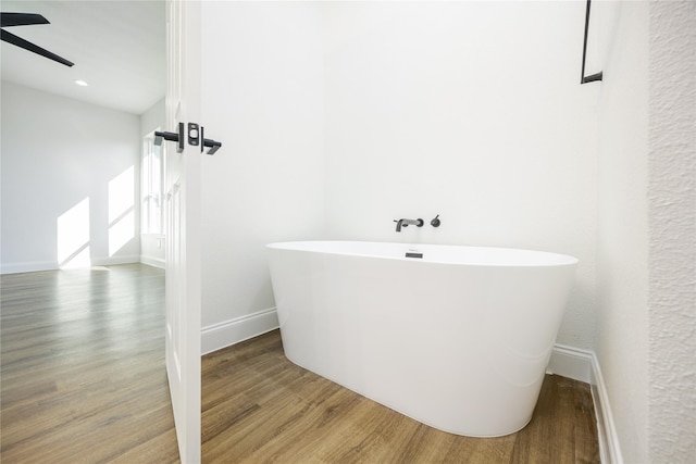 bathroom featuring hardwood / wood-style floors, a bath, and ceiling fan