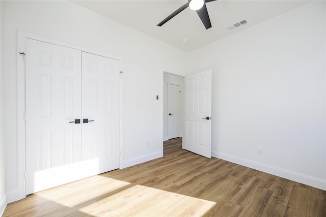 unfurnished bedroom with wood-type flooring, ceiling fan, and a closet