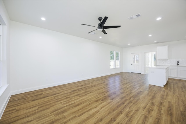 unfurnished living room with ceiling fan, sink, and light wood-type flooring