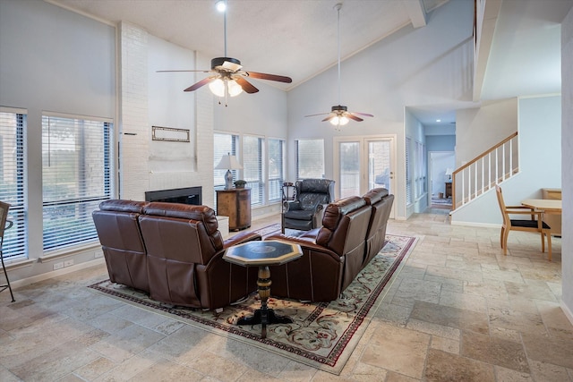 living room featuring ceiling fan, a large fireplace, a wealth of natural light, and high vaulted ceiling