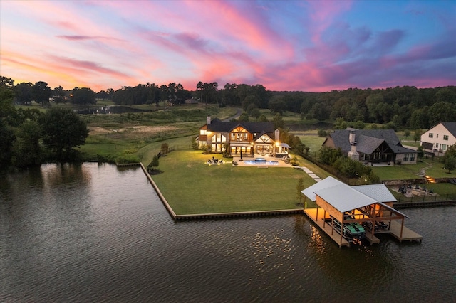 aerial view at dusk featuring a water view