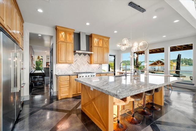 kitchen with a sink, recessed lighting, high end fridge, and wall chimney range hood