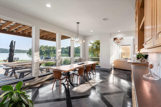 dining area with a water view and a notable chandelier