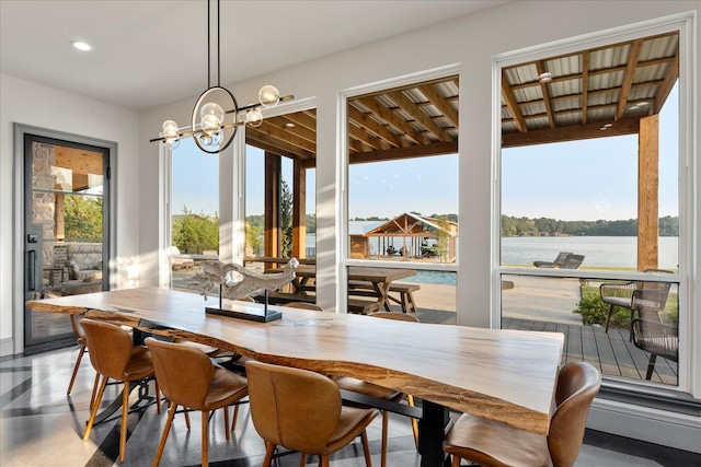 dining room featuring recessed lighting, a water view, and a notable chandelier