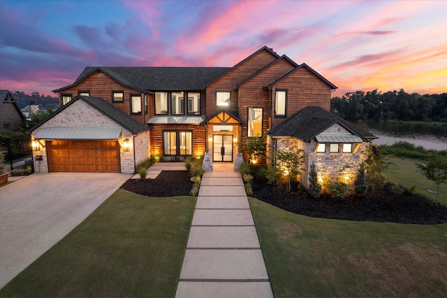 view of front of home featuring concrete driveway, a front lawn, stone siding, french doors, and an attached garage