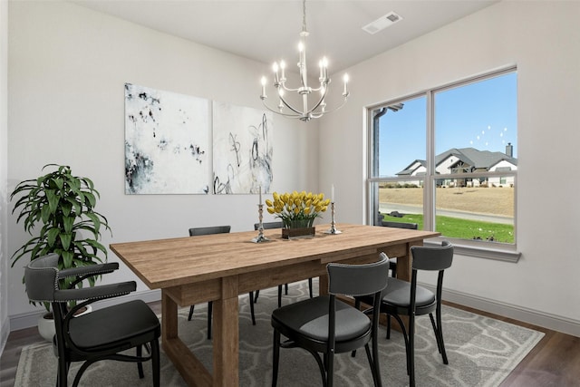 dining area with dark hardwood / wood-style flooring and an inviting chandelier