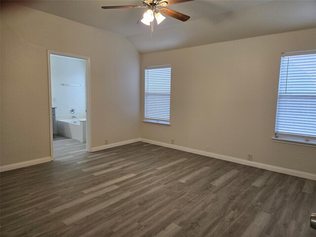 empty room featuring vaulted ceiling, plenty of natural light, ceiling fan, and dark hardwood / wood-style flooring