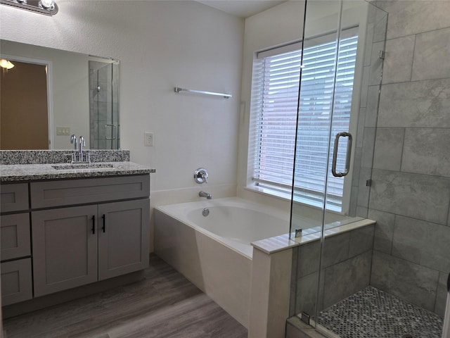 bathroom with hardwood / wood-style flooring, vanity, and separate shower and tub