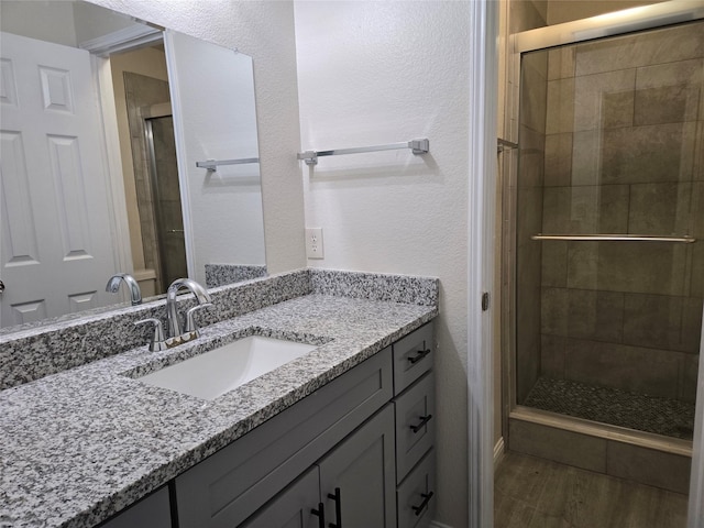 bathroom with vanity, wood-type flooring, and a shower with door