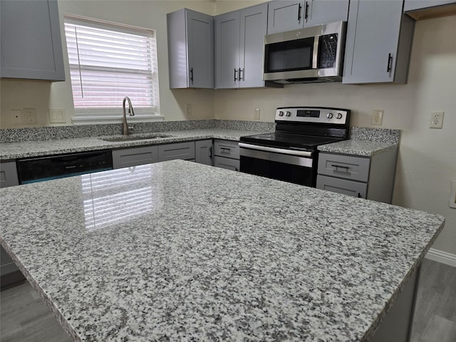 kitchen featuring appliances with stainless steel finishes, sink, gray cabinetry, and light stone counters