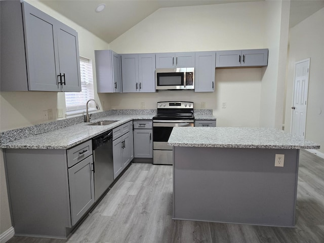 kitchen featuring lofted ceiling, sink, gray cabinetry, a center island, and stainless steel appliances