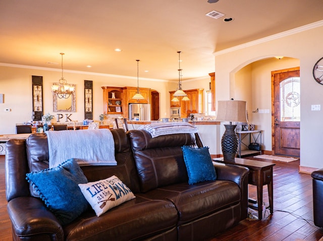 living room with ornamental molding, a healthy amount of sunlight, a chandelier, and dark hardwood / wood-style flooring