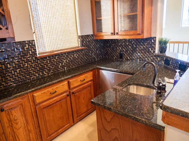 kitchen featuring tasteful backsplash, dishwashing machine, sink, and dark stone countertops