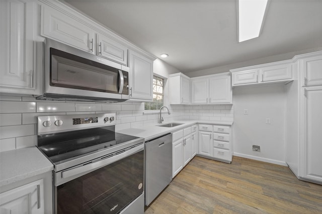 kitchen with sink, white cabinetry, stainless steel appliances, light hardwood / wood-style floors, and decorative backsplash