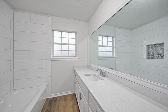 bathroom with tiled shower / bath, vanity, hardwood / wood-style floors, and plenty of natural light