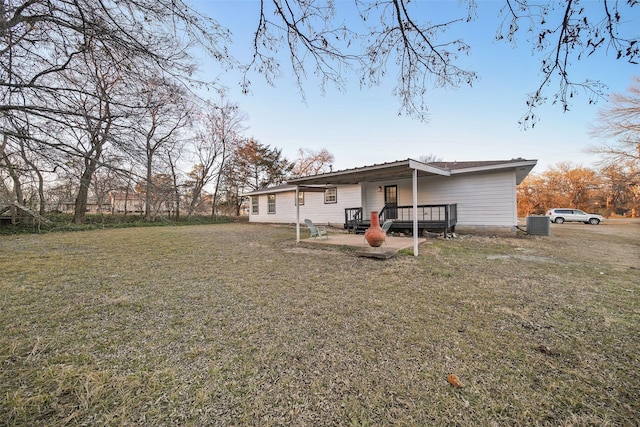 rear view of house featuring cooling unit, a wooden deck, a yard, and a patio