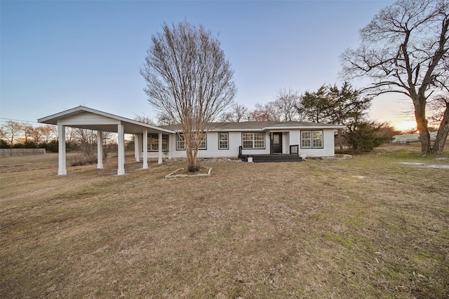 ranch-style home with a lawn and a carport