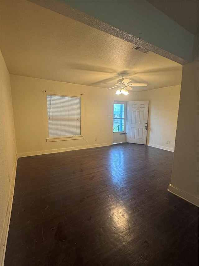 3033 Anita Dr, Garland, TX 75041 - empty room featuring ceiling fan, a textured ceiling, baseboards, visible vents, and dark wood-style floors