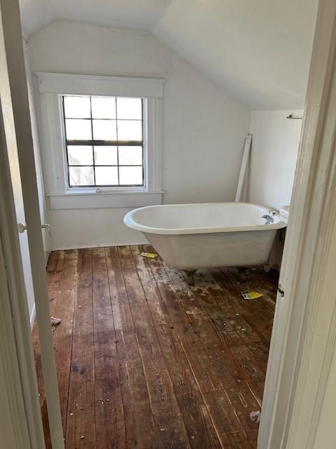 bathroom with wood-type flooring, vaulted ceiling, and a bathtub