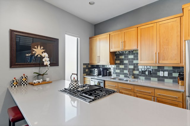 kitchen featuring stainless steel appliances, a kitchen breakfast bar, sink, and backsplash