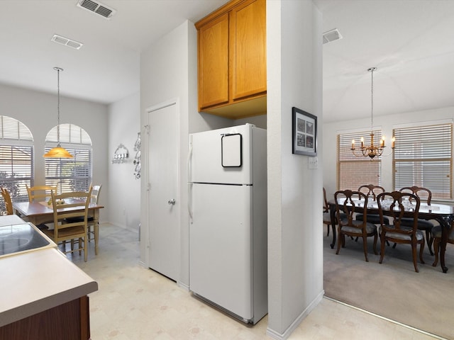 kitchen featuring white refrigerator, a chandelier, light carpet, and pendant lighting