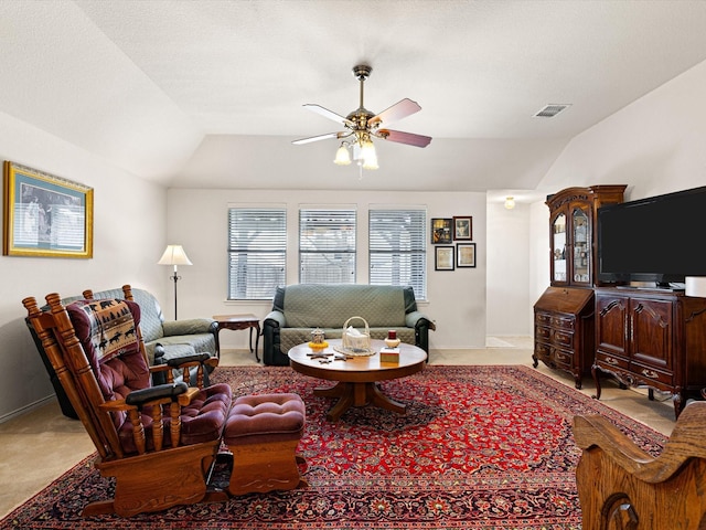 living room featuring ceiling fan, lofted ceiling, carpet flooring, and a textured ceiling